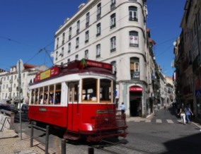 Tram listrik tua melintasi liuk jalan kota tua Lisbon